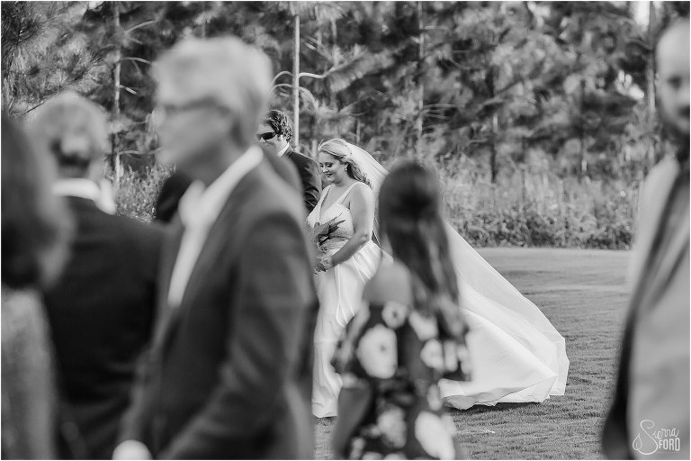 a peek through their guests as bride's brother walks her down the aisle at Mission Inn wedding on Little Lake Harris