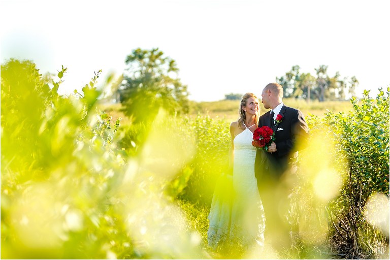 bride & groom look lovingly at each other as they walk among the rows of blueberry bushes at Central Florida winery wedding