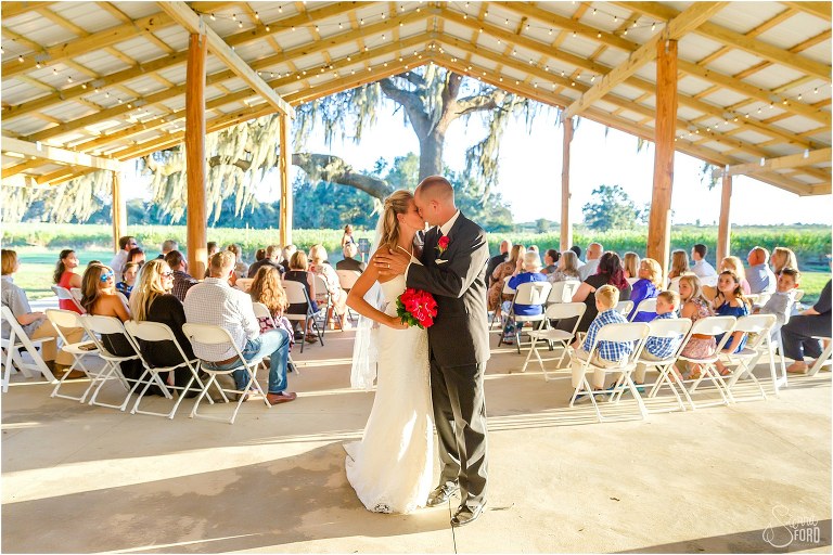 Bride & groom kiss at end of aisle as loved ones look on at Central Florida winery wedding