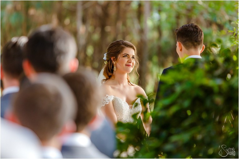 bride looks lovingly at groom as he says his vows to her at Club Lake Plantation wedding ceremony