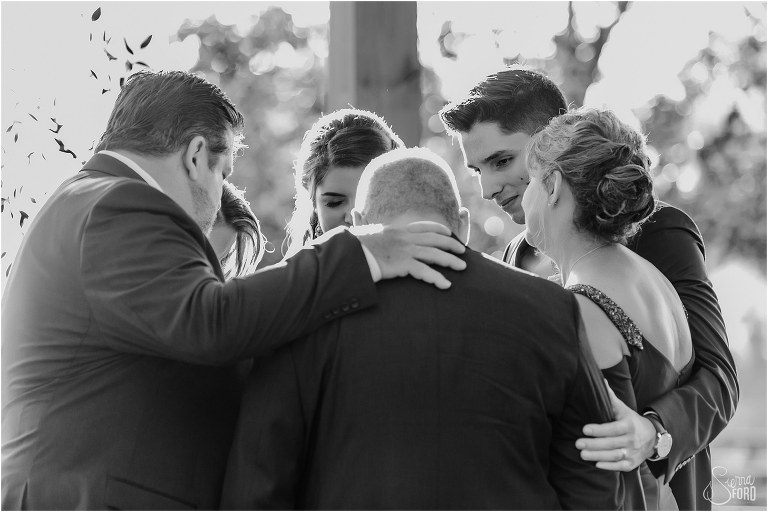 families of bride & groom share a group hug during emotional Club Lake Plantation wedding ceremony