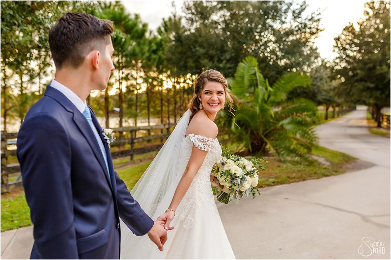 bride smiles looking back at groom as they walk after Club Lake Plantation wedding