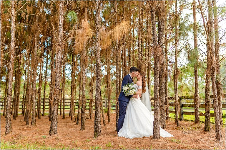 bride & groom kiss among the bare pine trees after Club Lake Plantation wedding