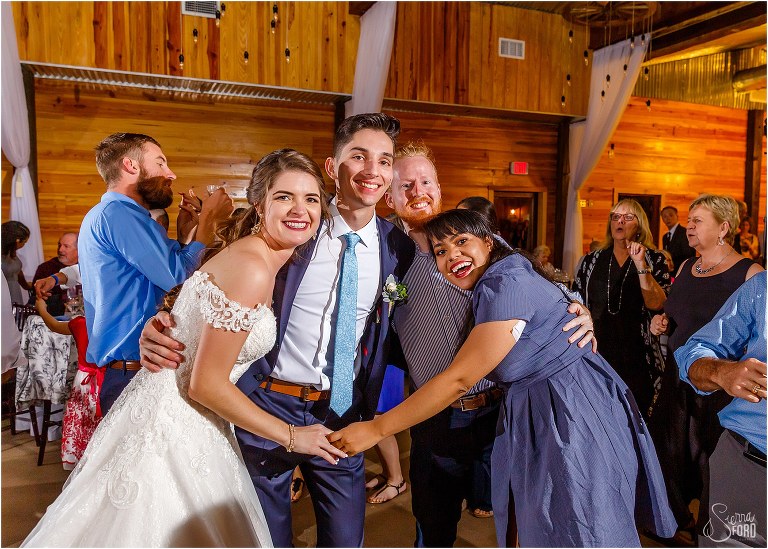 bride & groom pose on the dance floor with their guests at Club Lake Plantation wedding reception