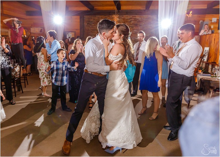 bride & groom kiss on the dance floor as crowd cheers at Club Lake Plantation wedding reception