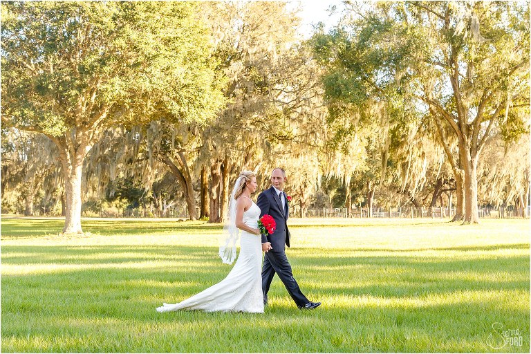 bride & groom stroll hand in hand through field at Central Florida winery wedding