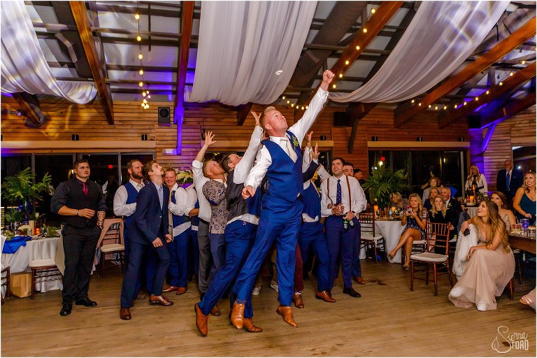 groomsmen jumps in the air to try to catch garter at Amelia Island wedding reception