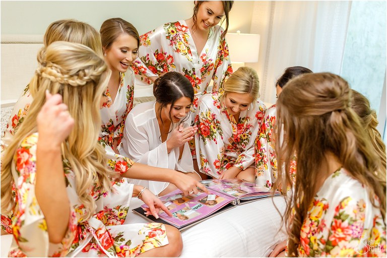 bride laughs with bridesmaids over surprise scrapbook before Amelia Island wedding