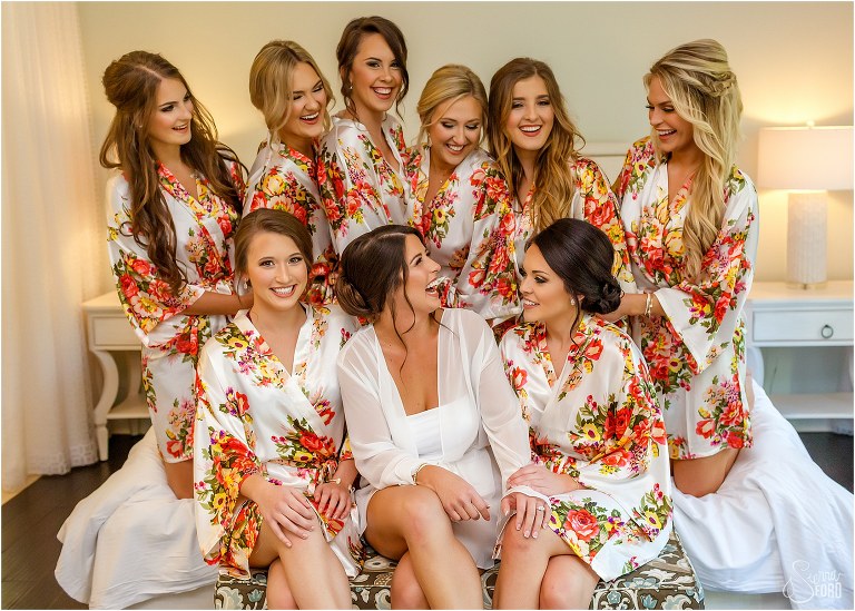 bride & bridesmaids laugh in matching floral robes before Amelia Island wedding