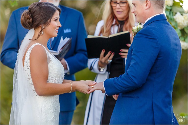 bride slips wedding ring on groom's finger during Amelia Island wedding ceremony