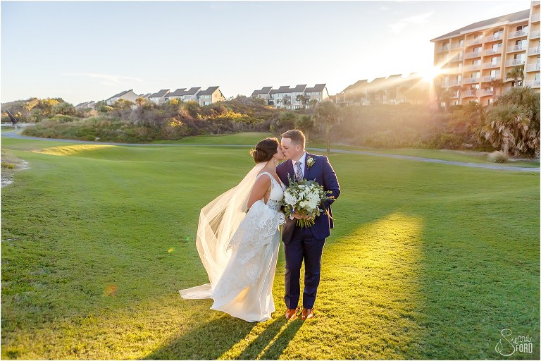 bride & groom kiss as sun flares over Walker's Landing at Amelia Island wedding
