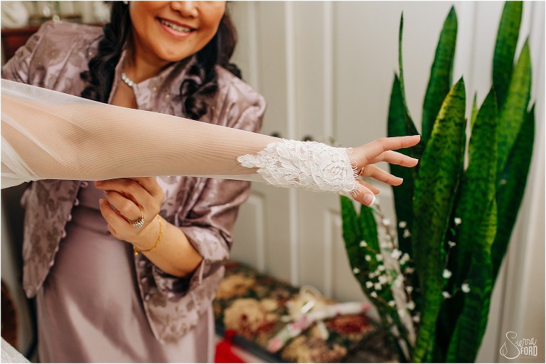 bride puts arm through lace sleeve of wedding dress before her Florida elopement