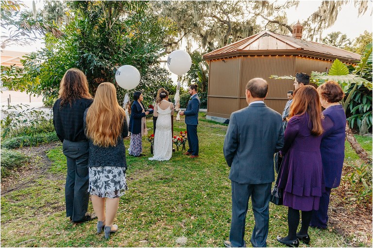 small group of loved ones look on as bride & groom exchange vows during Florida elopement