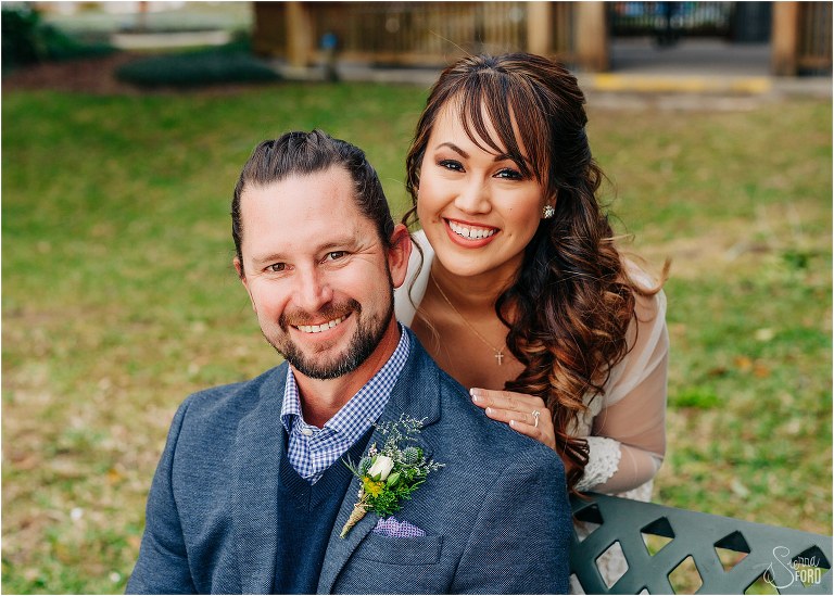 bride snuggles up behind groom in Wooten Park at Florida elopement