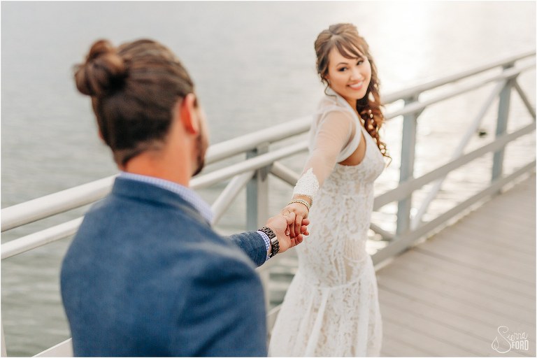 bride smiles back at groom as she leads him down the dock after Florida elopement