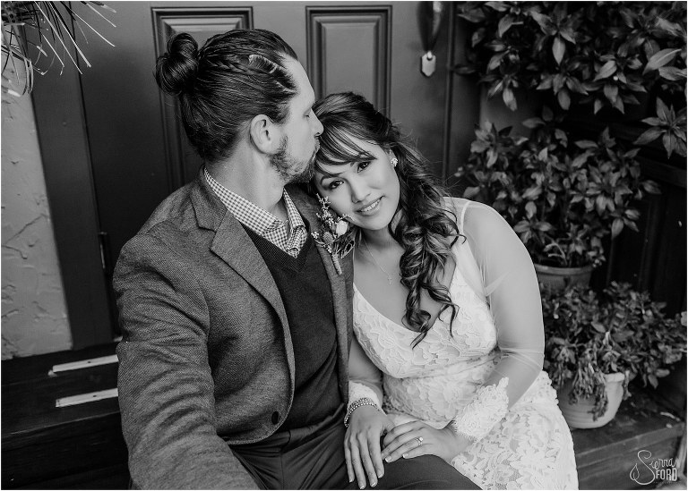 groom kisses bride's forehead while they sit on the Goblin market stoop at Florida elopement