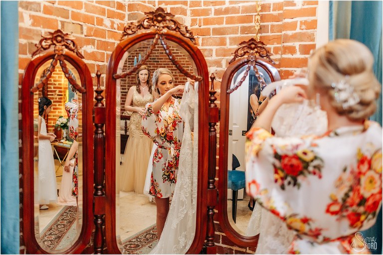 mother of the bride looks on as bride gets ready to put dress on before Town Manor wedding