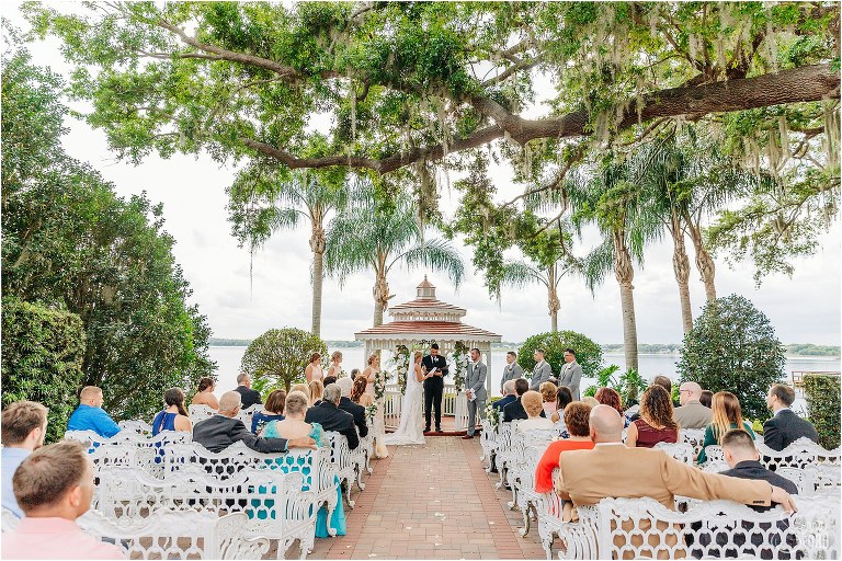 bride & groom exchange vows lakeside under Spanish moss at Town Manor wedding ceremony