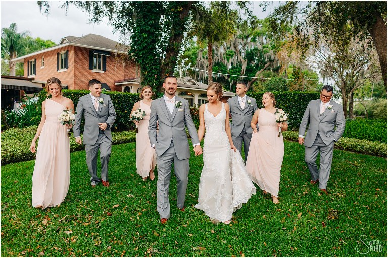 bride & groom laugh as they walk with their wedding party at Town Manor wedding