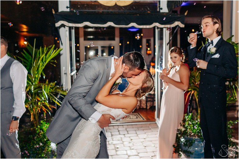 groom dips bride in kiss as guests blow bubbles during grand exit from Town Manor wedding