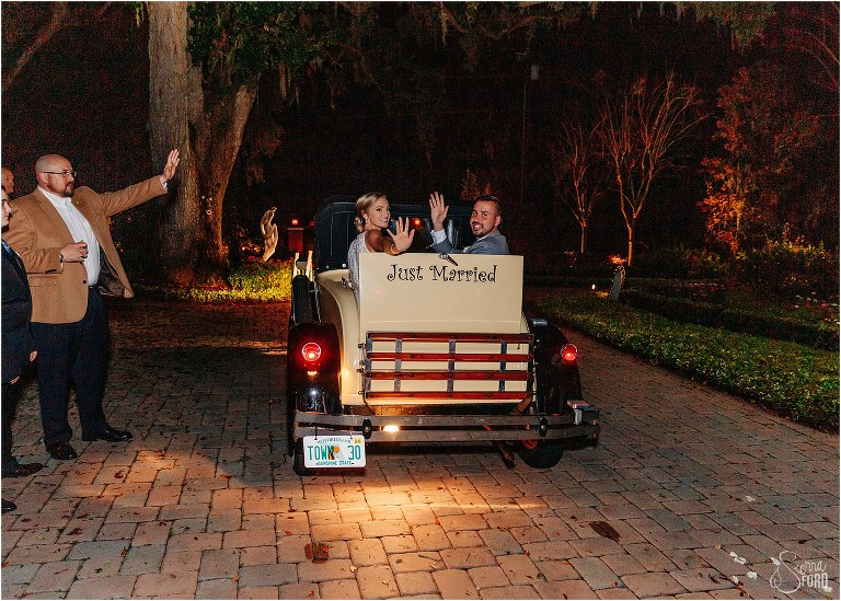 bride & groom wave goodbye as they drive off in antique towncar after Town Manor wedding