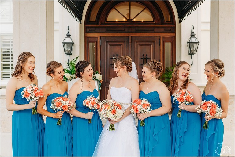 bride & bridesmaids laugh together in blue bridesmaids dresses before River House wedding