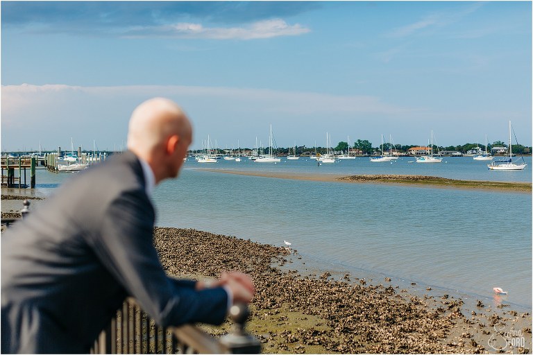 groom looks out at boats as he prepares for his River House wedding