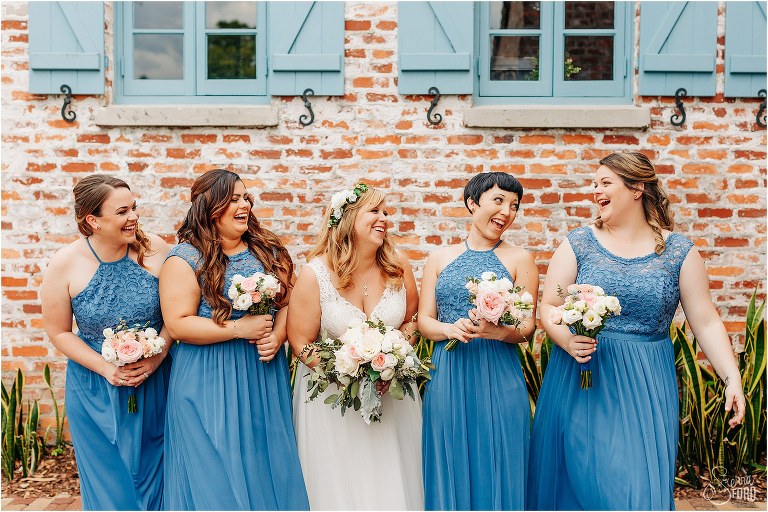 bride laughs with her bridesmaids in their blue varied flowy gowns before Winter Park wedding