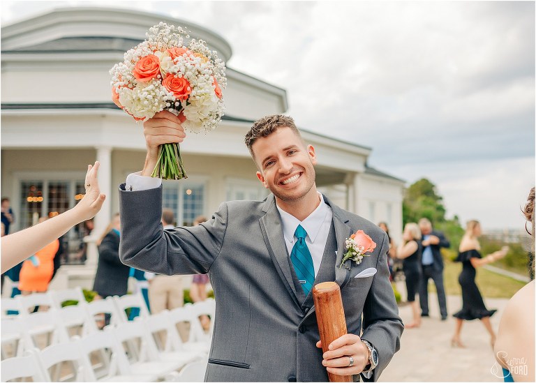best man takes his turn on bridal bouquet duty during pictures at River House wedding