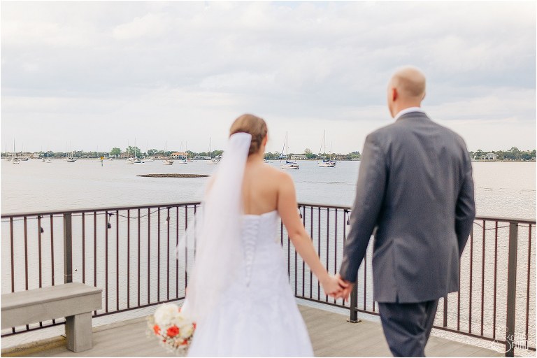 bride & groom walk to edge of dock to look at boats at River House wedding