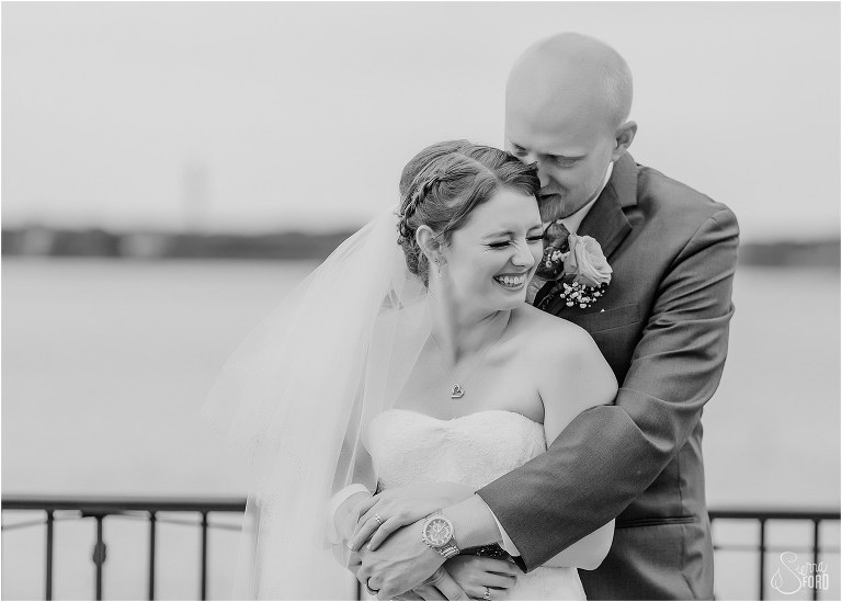 bride laughs as groom whispers in her ear at River House wedding