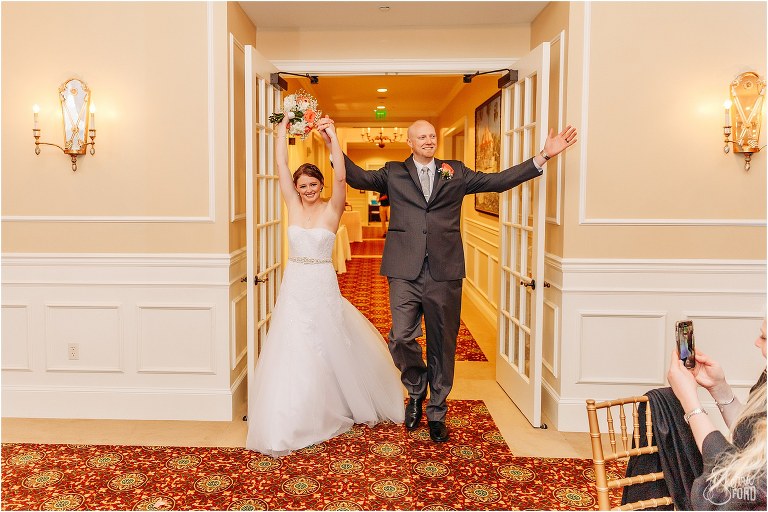 bride & groom throw their hands up as they enter River House wedding reception