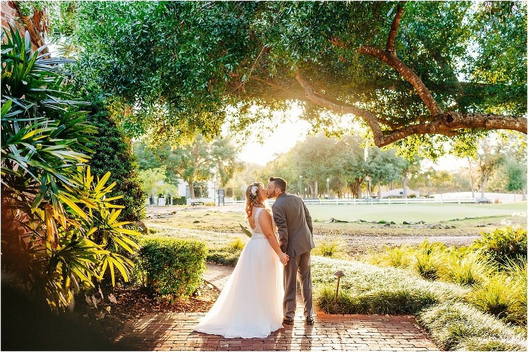 bride & groom kiss in Casa Feliz gardens as sun sets behind Winter Park wedding