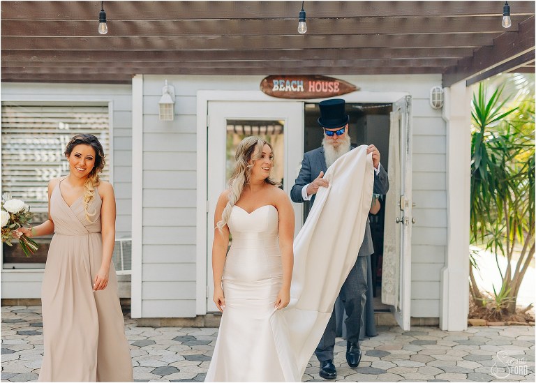 father of the bride carries train as she enters Disney themed garden wedding ceremony 