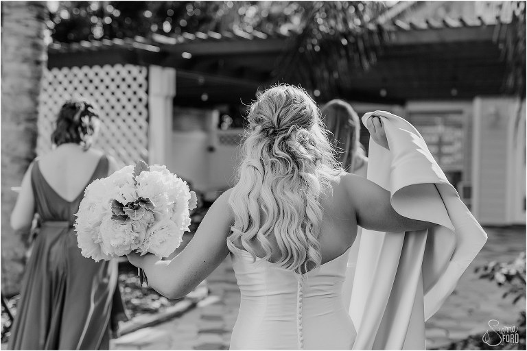 bride carries train as she walks back into bridal cottage before Disney themed garden wedding