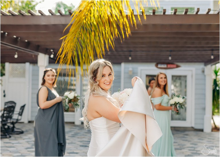 bride & bridesmaids smile over their shoulders as they walk to Paradise Cove's bridal cottage before Disney themed garden wedding