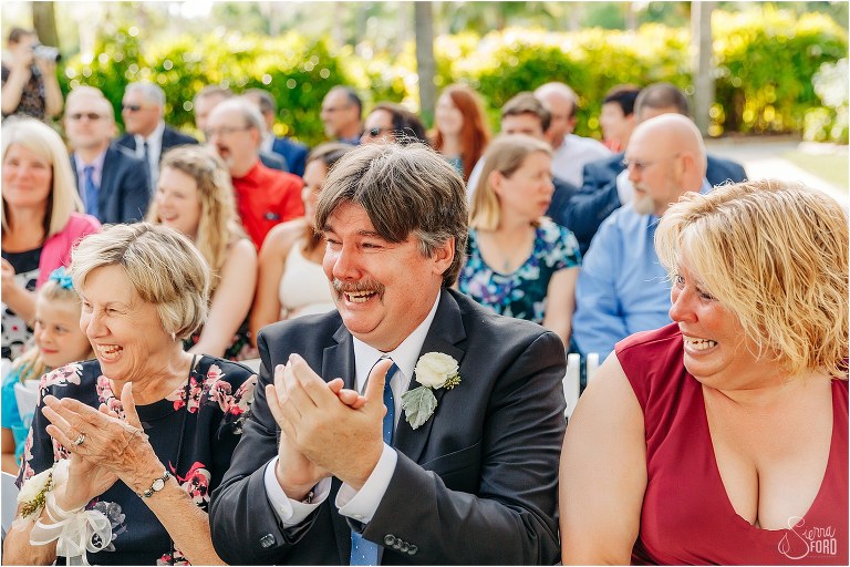 groom's family laughs and cheers as groom enters ceremony on boat at Disney themed garden wedding