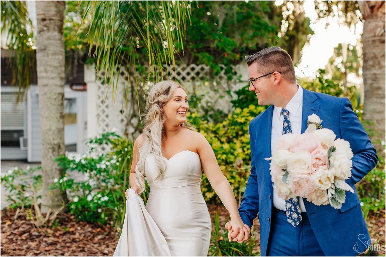 bride & groom walk hand in hand laughing at Disney themed garden wedding