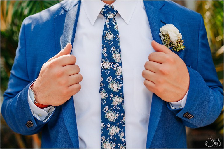 groom grips lapels of blue Hardwick suit before Disney themed garden wedding