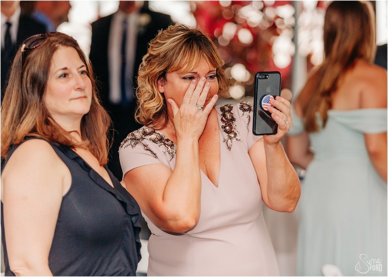 mother of bride wipes tear away as she watches first dance at Disney themed garden wedding reception