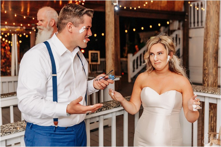 groom makes funny face at bride after getting icing in her hair at Disney themed garden wedding reception