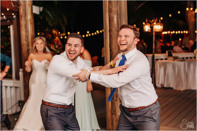 groomsmen grab each other for favorite song at Disney themed garden wedding reception