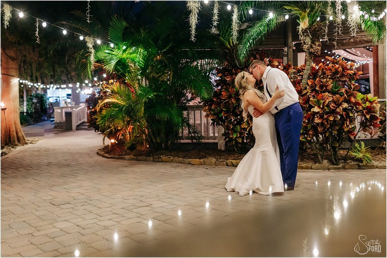 bride & groom share a kiss under market light reflection at Disney themed garden wedding