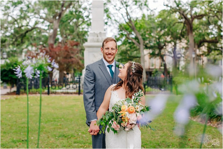 bride looks up at smiling groom through purple flowers at Savannah elopement