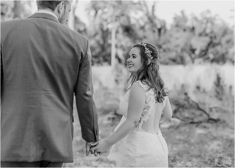 bride smiles up at groom as they walk hand in hand through Wormsloe Plantation after Savannah elopement