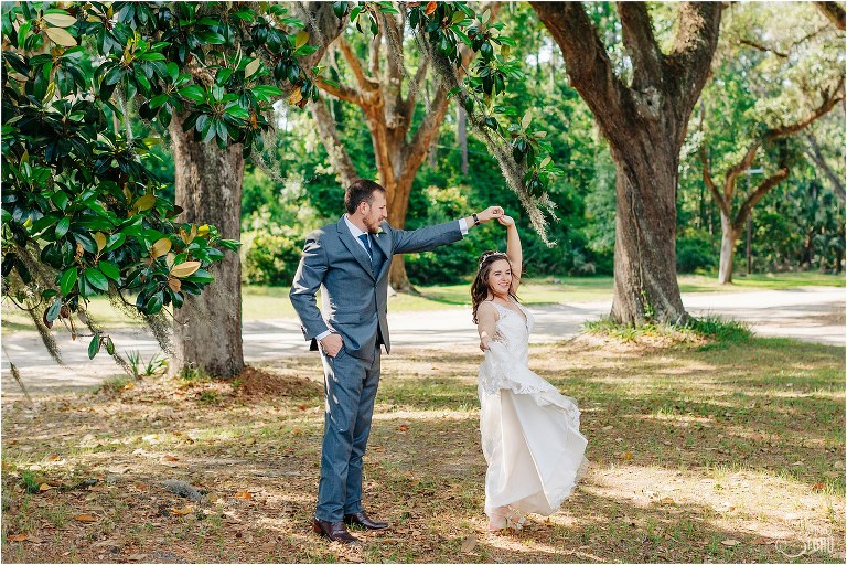 groom spins bride under oak trees at Wormsloe Plantation after Savannah elopement