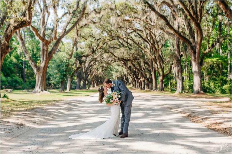 groom dips his bride for a kiss under the oak trees at Wormsloe Plantation after Savannah elopement