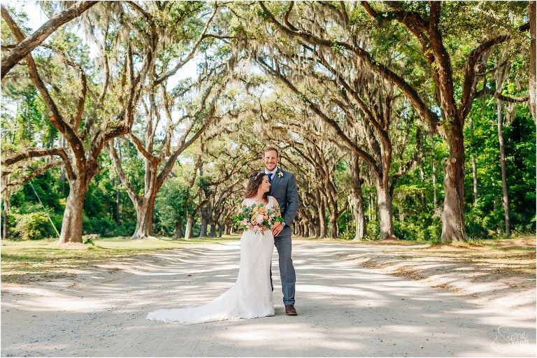 bride & groom embrace under lane of huge trees at Savannah elopement
