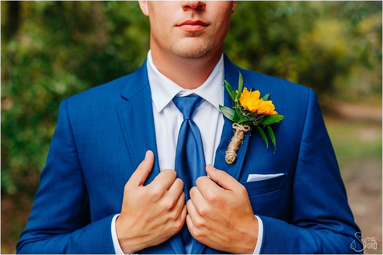 groom holds lapels of blue Men's Wearhouse suit before DIY Florida Barn Wedding