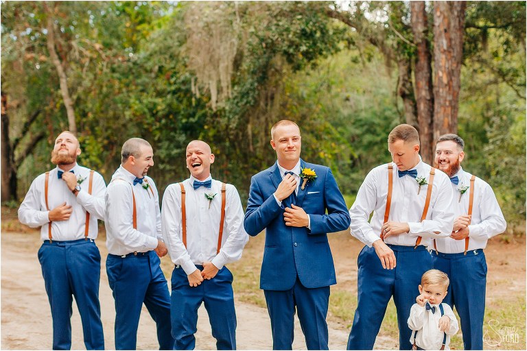 groom laughs with groomsmen as they get ready for DIY Florida Barn Wedding 